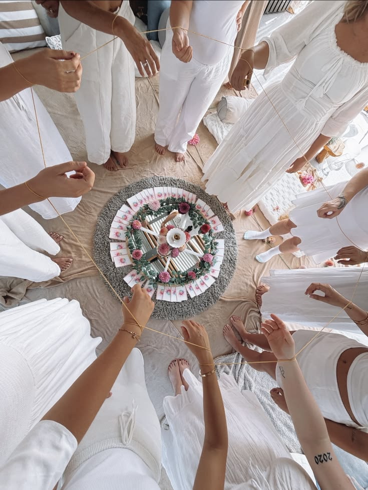 Participantes en círculo alrededor de un altar floral sosteniendo un hilo