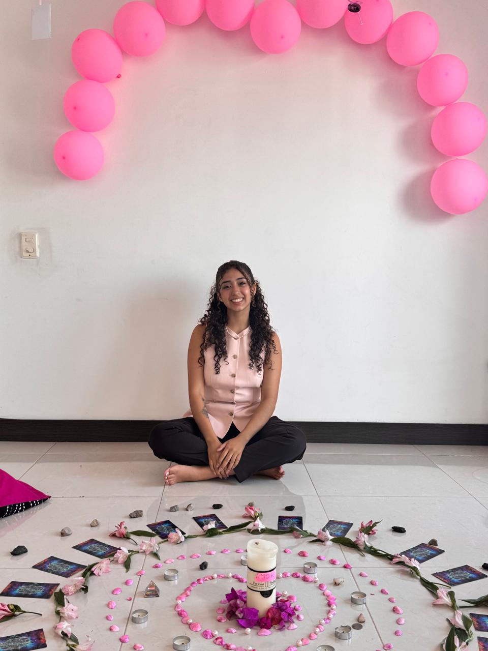 Celebración de cumpleaños con globos rosados y un altar de flores y velas